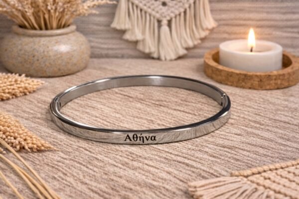 Ατσάλινη χειροπέδα σε ασημι απόχρωση, χαραγμένη με το όνομα ΑΘΗΝΑ.