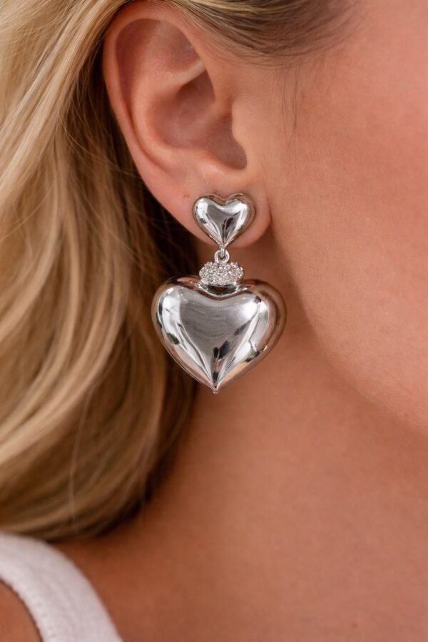Σκουλαρίκια σε ασημί απόχρωση με εντυπωσιακό σχέδιο καρδιάς.